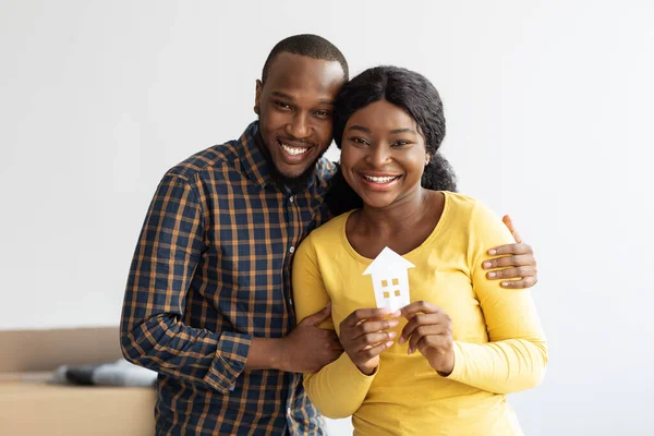 Conceito imobiliário. Felizes cônjuges afro-americanos segurando papel casa figura — Fotografia de Stock