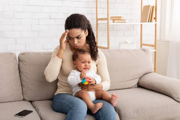 Afrikanische Mutter mit weinendem Säugling leidet unter Kopfschmerzen — Stockfoto