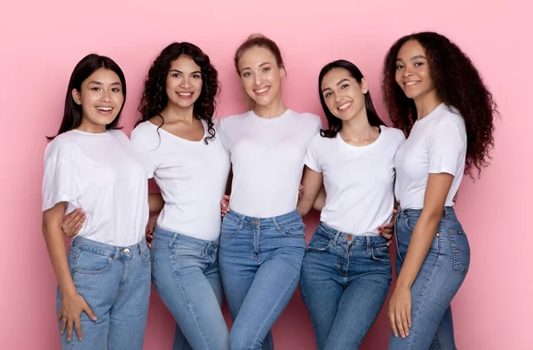 Grupo de cinco felices damas multirraciales abrazando sobre fondo rosa — Foto de Stock