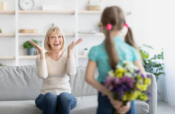 Back view of girl greeting woman with flowers — Stock Photo, Image