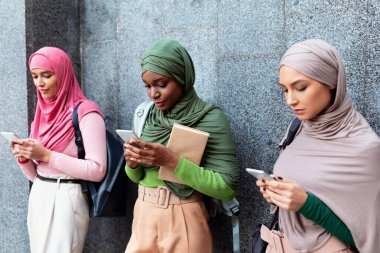 Çeşitli İslamcı Kadınlar Gri Duvarın Üzerinde Duran Telefonları Kullanıyor