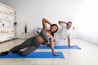 Evdeki yoga minderlerinin üzerinde yan tahtada duran mutlu siyah çift, boşluğu kopyala