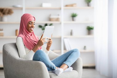 Genç Siyahi Müslüman Kadın Dijital Tabletle Sandalyede Rahatlıyor