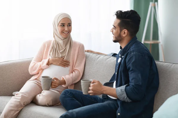 Glückliches werdendes Paar aus dem Nahen Osten, das sich zu Hause auf der Couch ausruht — Stockfoto