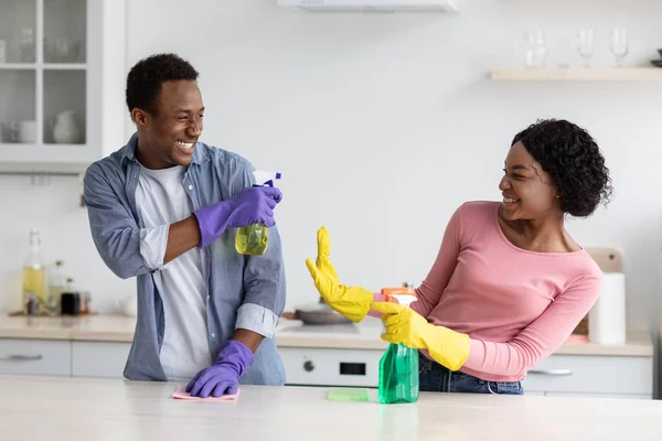 Fröhliche schwarze Haushälterinnen haben Spaß beim Küchenputzen — Stockfoto