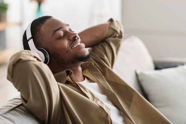 Afrikai srác hallgat zenét viselő vezeték nélküli fülhallgató otthon — Stock Fotó