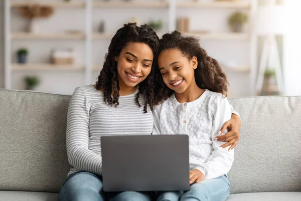 Gelukkig afrikaanse amerikaanse moeder en dochter met behulp van laptop samen — Stockfoto