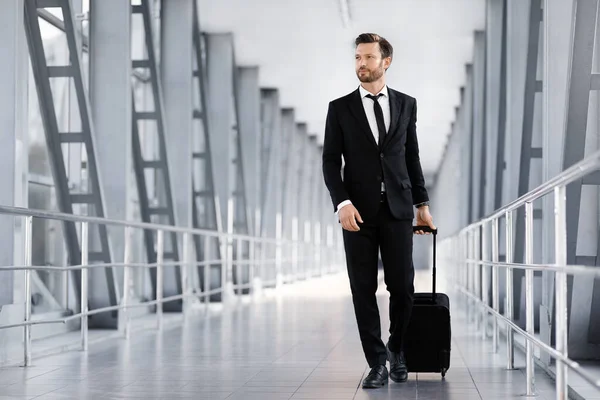 Geschäftsmann mittleren Alters läuft mit Gepäck am Flughafen-Terminal vorbei — Stockfoto