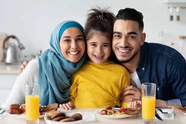 Küçük kızı olan mutlu İslami ebeveynler mutfakta poz veriyor, birlikte öğle yemeği yiyorlar. — Stok fotoğraf