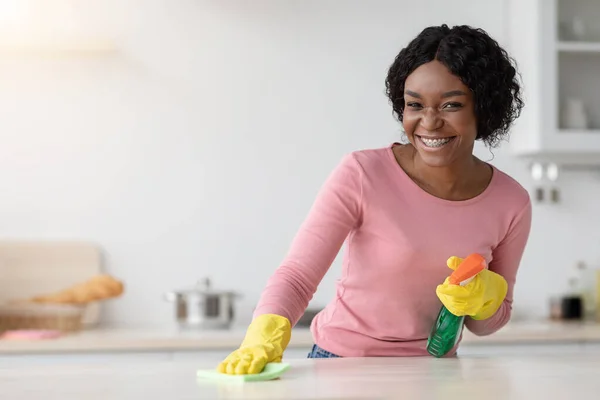 Glückliche afrikanisch-amerikanische Haushälterin putzt Tisch — Stockfoto