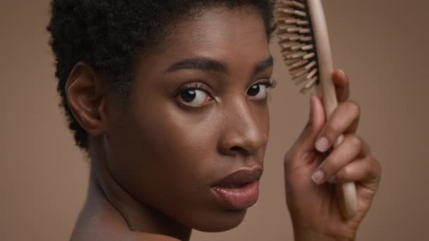 Mujer afroamericana cepillando el cepillo de pelo corto, fondo beige — Vídeo de stock