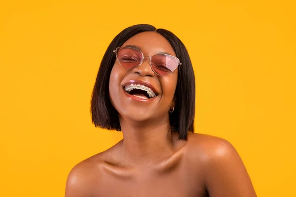 Portré vidám fekete nő napszemüvegben nevetés, kifejező pozitív érzelmek narancs stúdió háttér — Stock Fotó