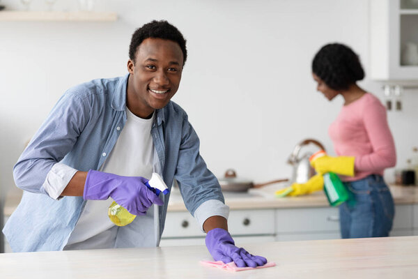 Cheerful black guy and lady cleaning their new house