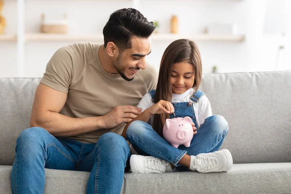 Niña y papá ahorrando dinero en alcancía —  Fotos de Stock