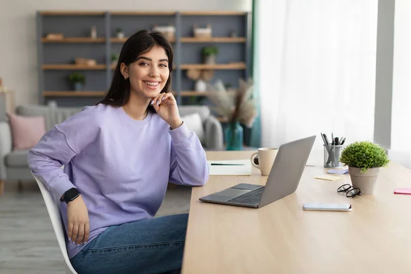 Portret van een lachende jonge vrouw aan het bureau — Stockfoto