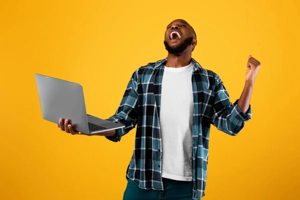 Overhappy Afro-Amerikaanse man houdt laptop Gesturing Ja, Gele achtergrond — Stockfoto