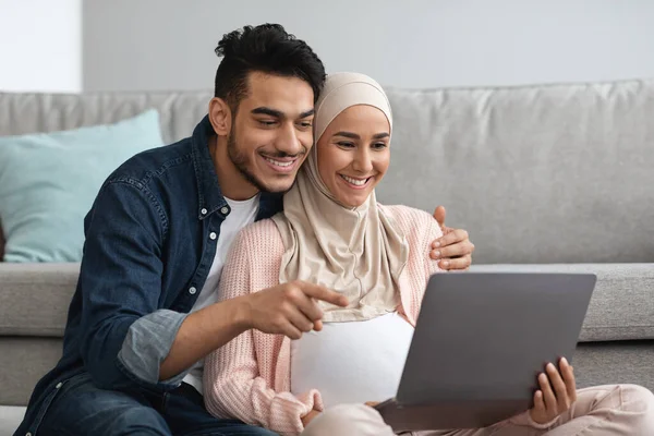 Glada Gravid Muselman Kvinna Och Hennes Make Använda Laptop Hemma Tillsammans — Stockfoto