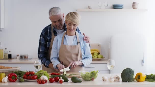 Esposo amoroso abrazando esposa mientras ella preparando la cena en la cocina — Vídeos de Stock