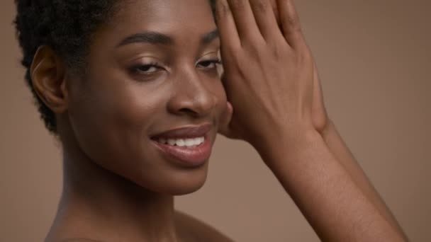 Atractiva mujer negra posando rostro y cuello conmovedores, fondo beige — Vídeo de stock
