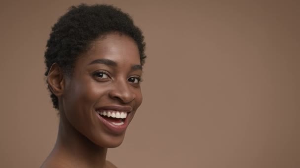 Porträt einer verspielten Afroamerikanerin, die auf beigem Hintergrund posiert — Stockvideo