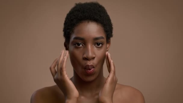 Afro-americana dama haciendo fachada masaje sonriendo sobre beige fondo — Vídeo de stock