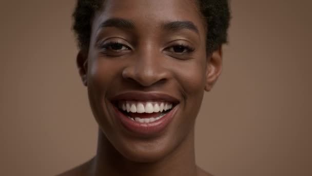 Feliz mujer afroamericana sonriendo a la cámara sobre fondo beige — Vídeo de stock