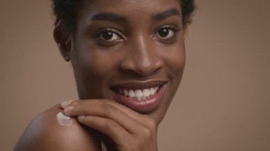 Omuzuna nemlendirici süren Afrikalı Amerikalı Kadın, Bej Arkaplan