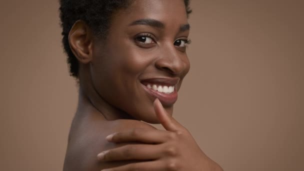 Shirtlose Afroamerikanerin, die die Schulter berührt, lächelt auf beigem Hintergrund — Stockvideo