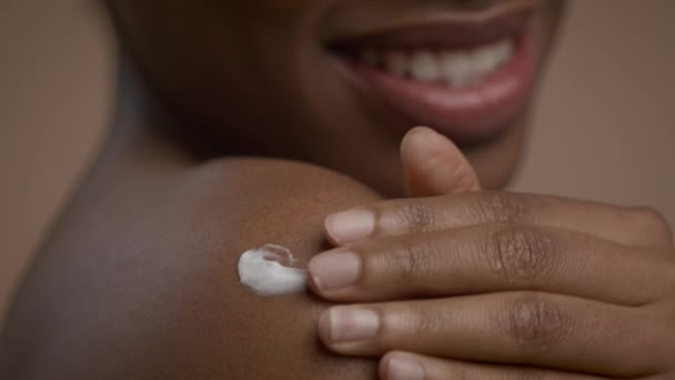 Black Woman Applying Cream On Shoulder Over Beige Background, Closeup — Stock Video
