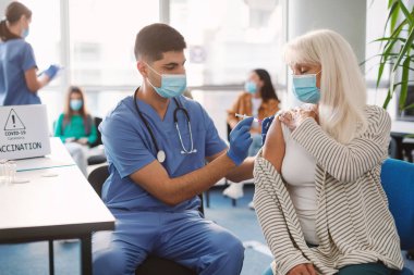 Coronavirus aşısı olan kıdemli hasta tıp merkezinde oturuyor.