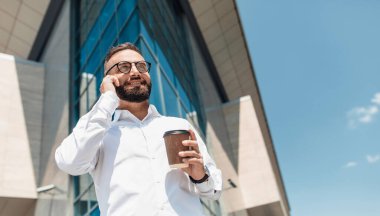 İş adamı ya da menajer tatilde müşteriyle konuşuyor, şehirde yürüyor, kahve içiyor, fotokopi çekiyor.