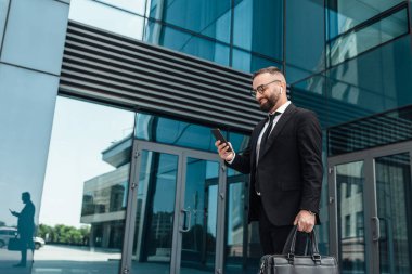 İşten ayrılırken en sevdiği müzik. Gülümseyen olgun iş adamı molada dışarıda yürüyor.