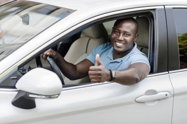 Щасливий чорний чоловік керує розкішною білою машиною, показуючи великий палець вгору — стокове фото