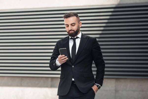 Estilo de vida empresarial. Homem de negócios maduro elegante navegar na internet no smartphone enquanto caminha na área urbana na cidade — Fotografia de Stock