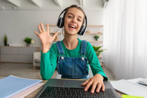 Chica sentada en la mesa, utilizando el ordenador portátil, saludando a la webcam — Foto de Stock