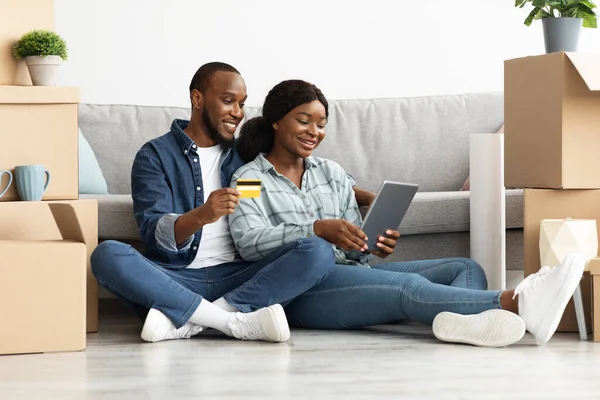 Χαμογελώντας νέους μαύρους συζύγους με ψηφιακή ταμπλέτα και πιστωτικές κάρτες ψώνια σε απευθείας σύνδεση — Φωτογραφία Αρχείου