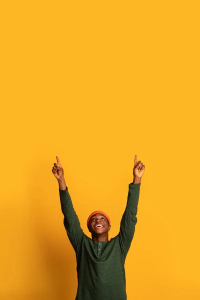 Kijk hier eens. Vrolijke Afrikaanse man wijzend op kopieerruimte boven hoofd — Stockfoto