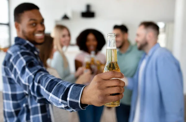 Garip siyahi adam bira şişesi gösteriyor, çeşitli arkadaşlarıyla kutlama yapıyor, evde tezahürat yapıyor, yakın plan diyor. — Stok fotoğraf