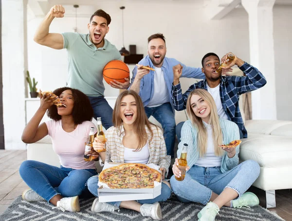 Groep van diverse jonge vrienden met pizza en bier kijken basketbal wedstrijd op TV, ondersteuning van favoriete team thuis — Stockfoto