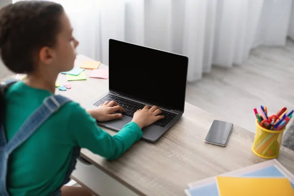 Menina sentada na mesa, usando laptop em branco, digitando no teclado — Fotografia de Stock