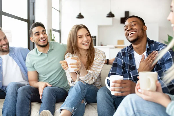 Grupo de amigos diversos passar o tempo juntos no fim de semana, segurando bebidas quentes, conversando e rindo de casa — Fotografia de Stock