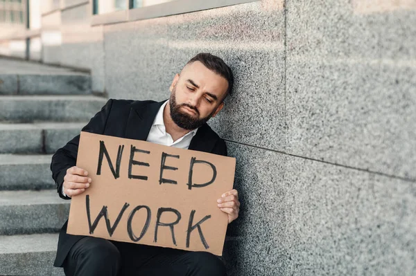 Ofis merkezinin yakınındaki merdivenlerde otururken, elinde poster tutan umutsuz, olgun bir adamın işi var. — Stok fotoğraf