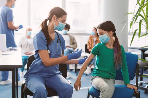 Mädchen erhält Covid-Impfstoff-Injektion im Sitzen mit Arzt in Klinik — Stockfoto