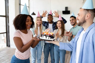 Doğumgünlerini kutlayan bir grup çok ırklı insan, evlerindeki zenci bayan arkadaşlarına lezzetli pastalarını sunuyorlar.