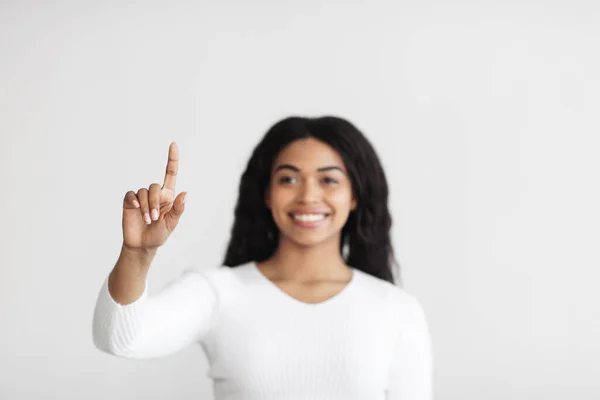 Розумний дім. Молода афроамериканка вказує пальцем у повітрі натискаючи кнопку невидимого екрану. — стокове фото