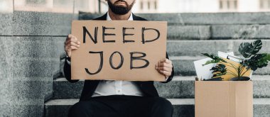 İşsizlik kavramı. Olgun bir işadamı posterle merdivenlerde oturuyor. İş lazım, kişisel eşyalar, mahsul.