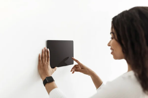 Innovative technology. African american lady using digital tablet with blank screen with smart home control system app