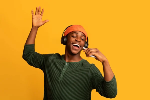 Technologien zum Spaß. Fröhlicher Schwarzer hört Musik über Kopfhörer und singt — Stockfoto