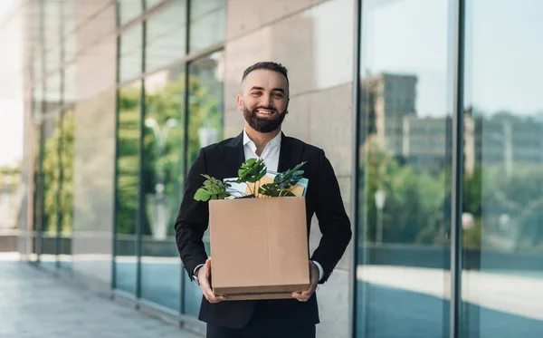 Šťastný dospělý podnikatel kráčející po ulici s krabicí věcí stěhujících se na nové pracoviště, kopírovat prostor — Stock fotografie