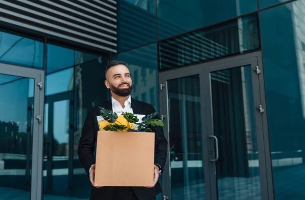 Feliz hombre de negocios maduro con caja moviéndose a lo largo del edificio de oficinas mientras vuelve a trabajar después de la cuarentena — Foto de Stock